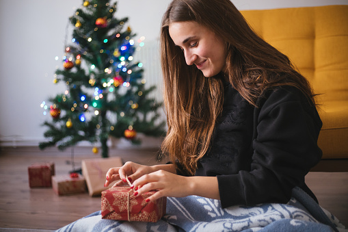 Woman in front of Christmas tree holding present