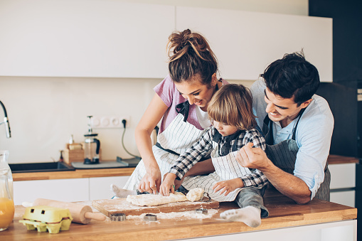Young family with a little boy preparing cookies together, with copy space