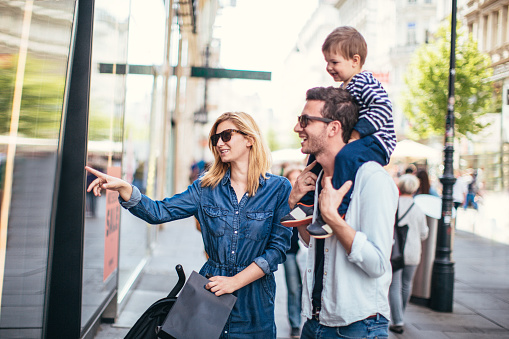 Photo of young happy family shopping around the city